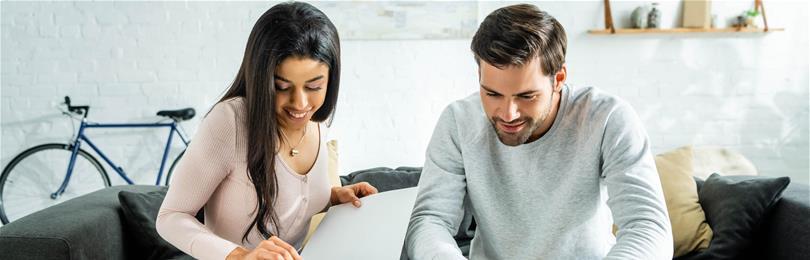 Couple_Reviews_Paperwork_Laptop_On_Couch