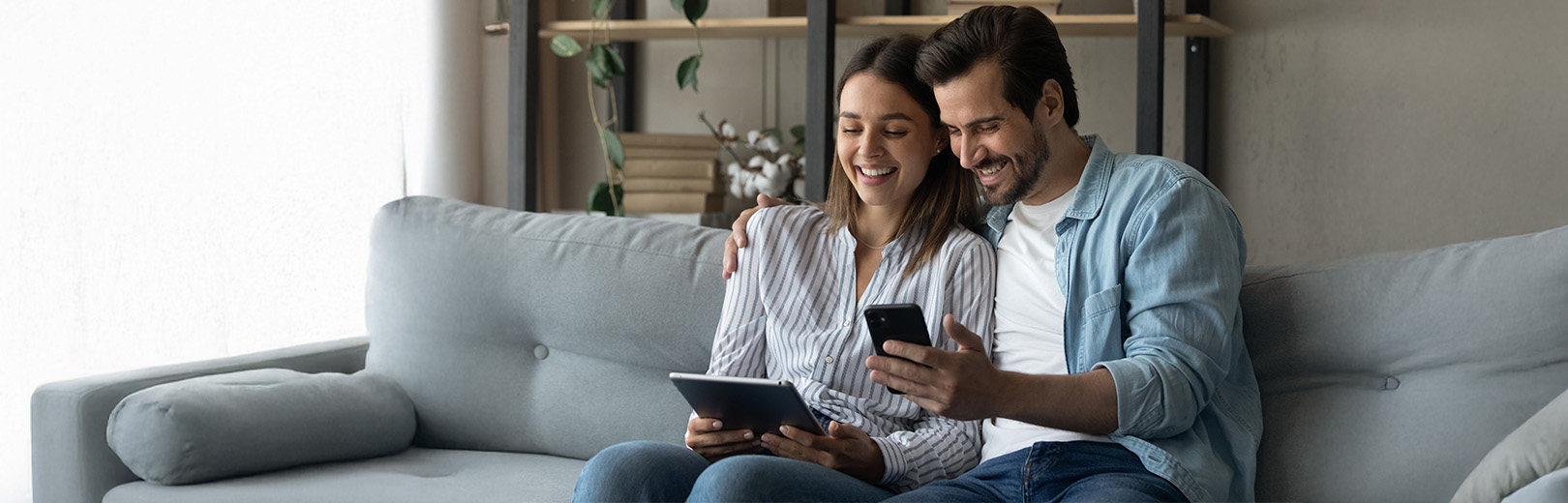 a couple looks at a phone and tablet